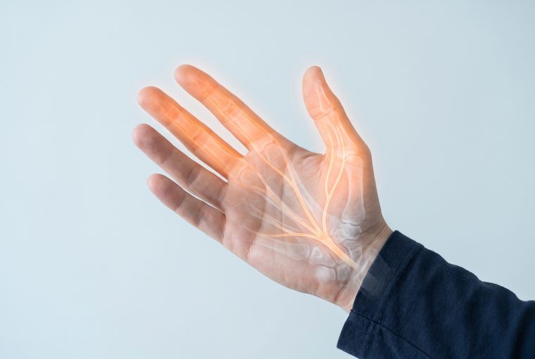 An open hand with the palm facing forward and the thumb, index and middle fingers glowing to show the area supplied by the median nerve.